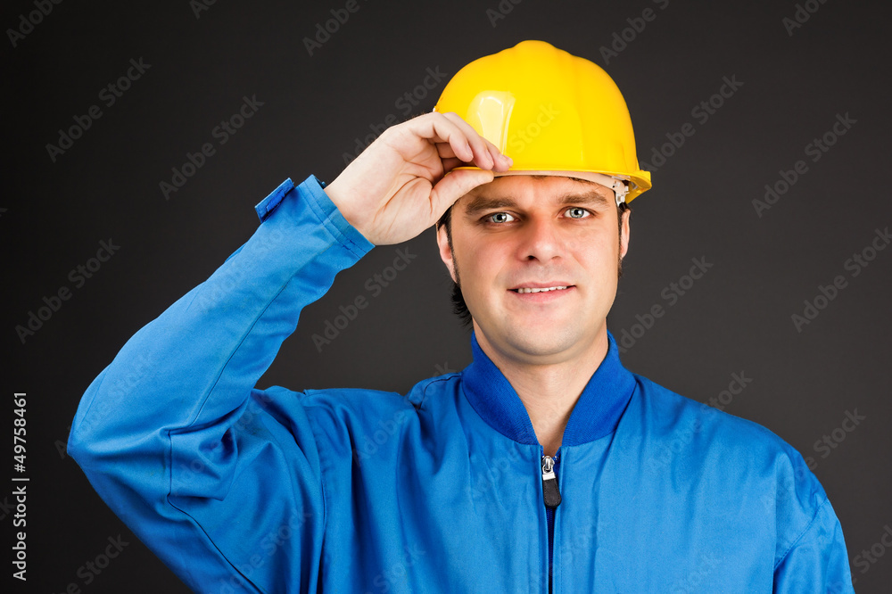 Young construction worker with his hand on hard hat brim Young construction worker with his hand on hard hat brim