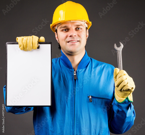 Portrait of a young worker holding a blank clipboard and a wrenc photo