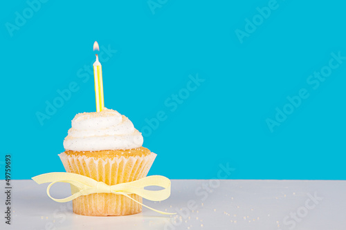 Single cupcake with lit yellow candle