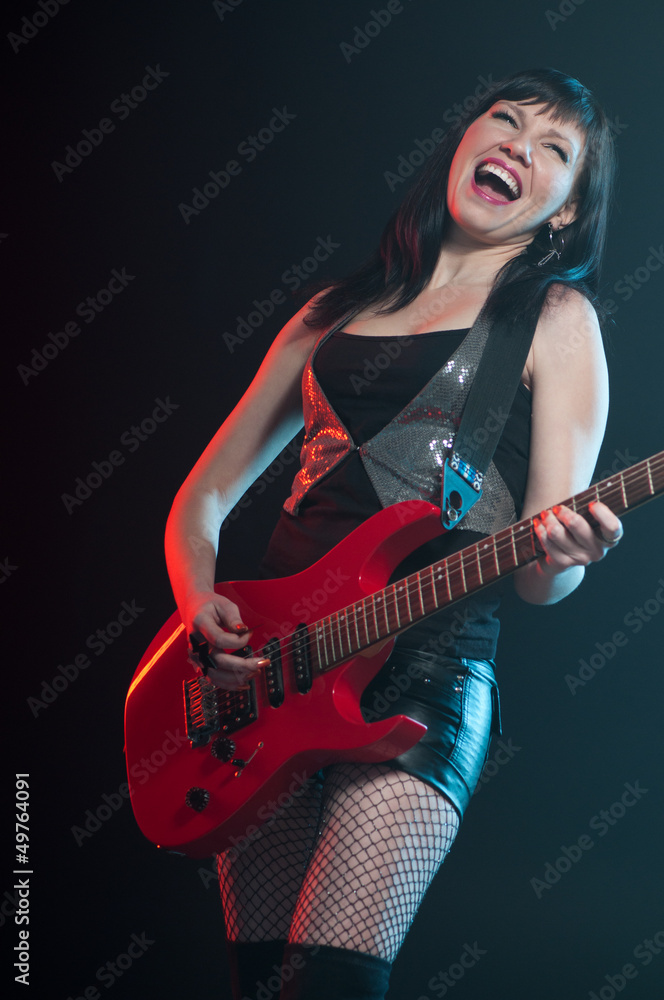 Expressive young woman playing the electric guitar, studio shot