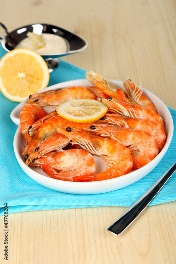 Shrimps with lemon on plate on wooden table close-up Shrimps with lemon on plate on wooden table close-up