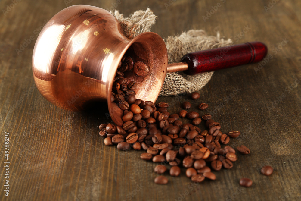 Coffee pot with coffee beans on wooden background