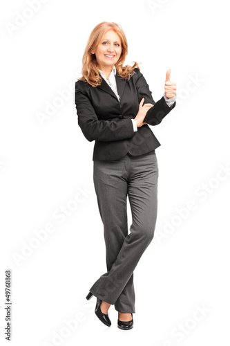 Full length portrait of a smiling businesswoman leaning on wall
