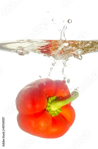 rote Paprika fällt ins Wasser vor weiß