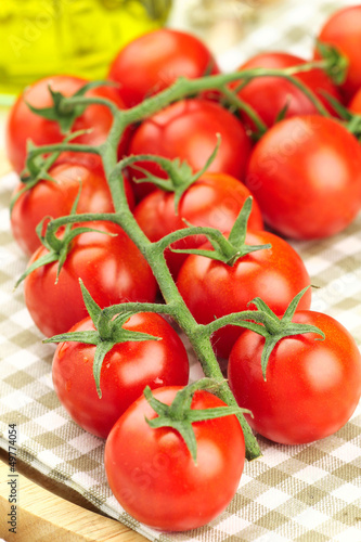 Red ripe cherry tomatoes on a vine on a kitchen towel