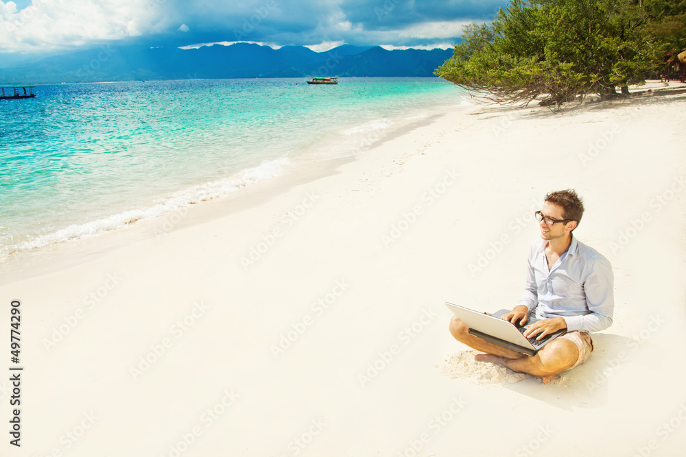man with laptop on colorful beach of island