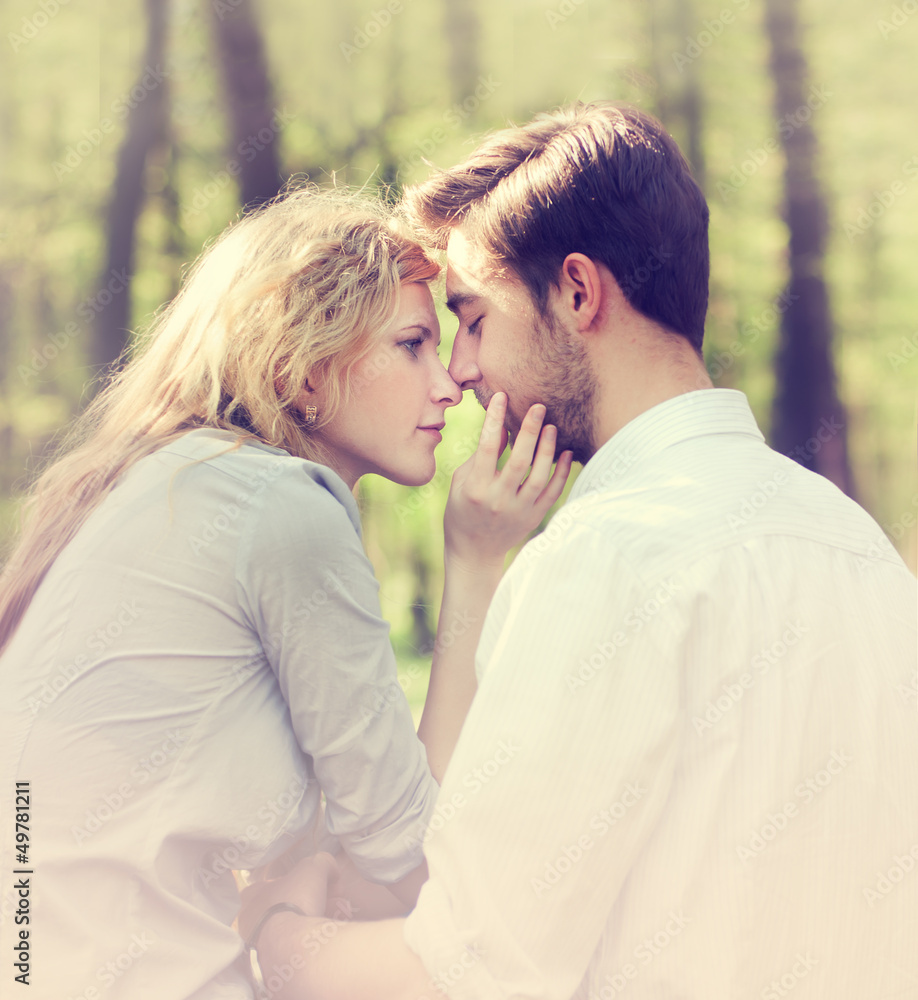 young couple kissing while sitting in a summer forest young couple kissing while sitting in a summer forest
