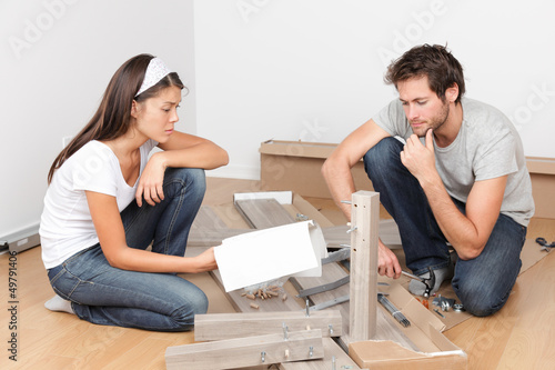 Couple moving in assembling bed furniture photo