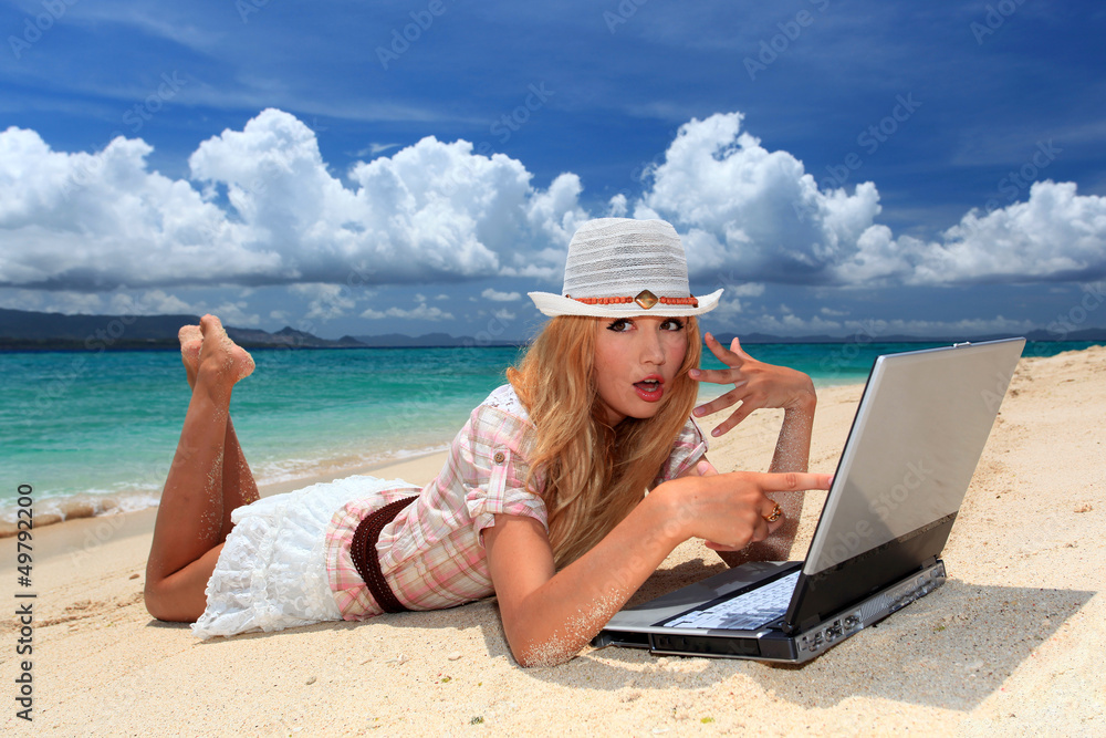 南国沖縄の美しいビーチでパソコンを楽しむ笑顔の女性