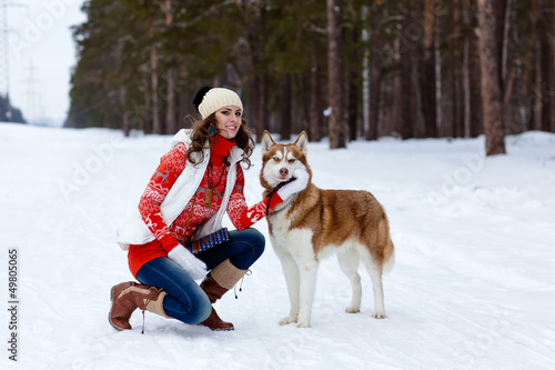 Happy woman playing with siberian husky dog in winter forest