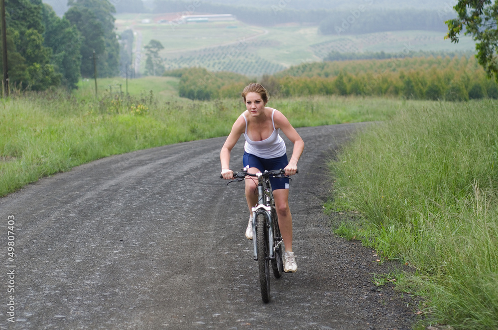 Girl riding mountain bike through forest