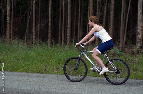 Girl riding mountain bike through forest