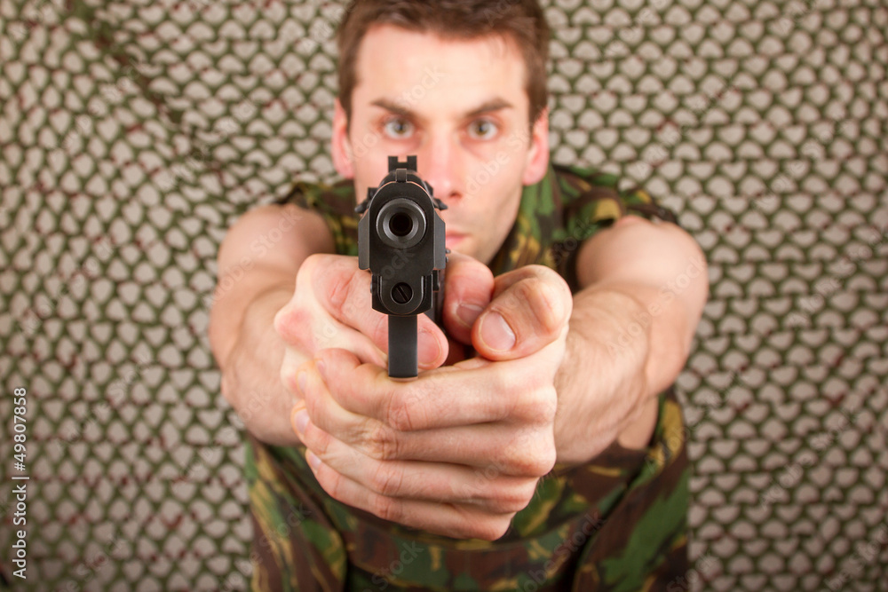 Soldier in camouflage vest is holding a gun Soldier in camouflage vest is holding a gun
