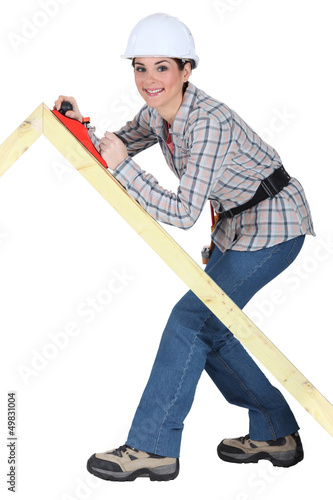 Tradeswoman using a plane to smooth a wooden frame