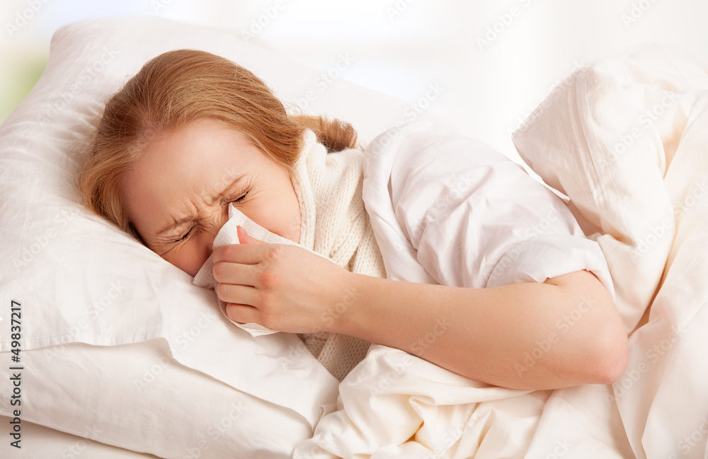 ill sick young woman sneezes into a handkerchief in bed ill sick young woman sneezes into a handkerchief in bed