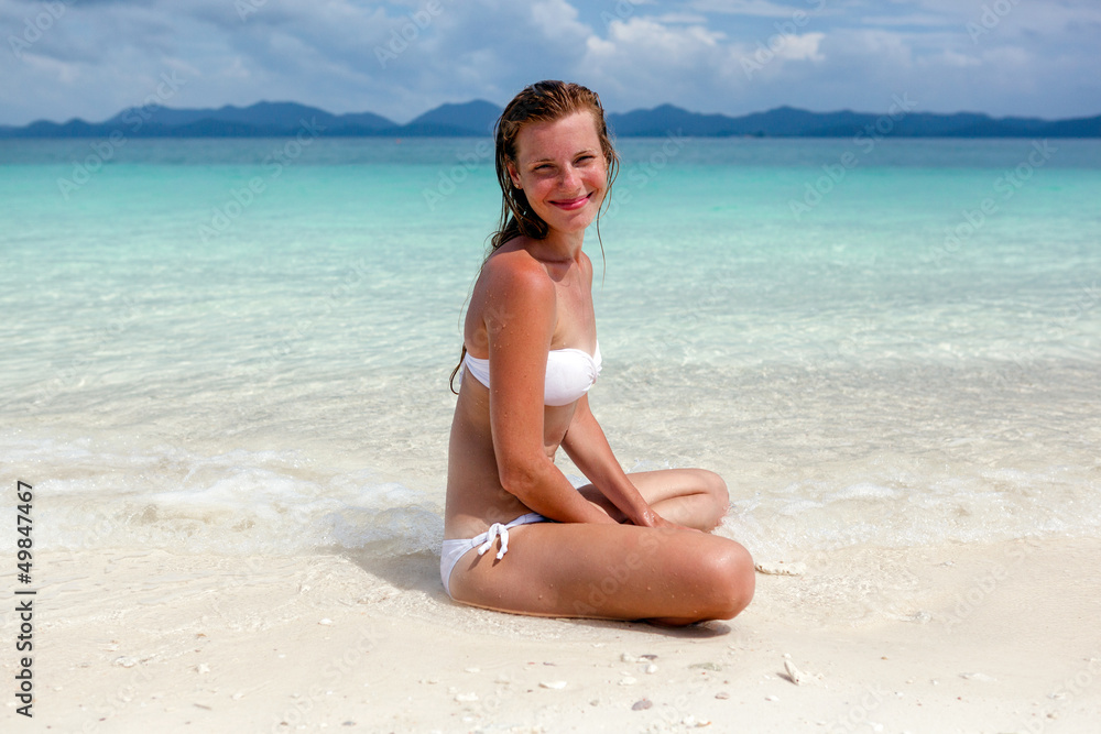 Beautiful young woman in bikini on the sunny tropical beach rela