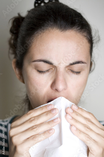 Frau niest in ein Taschentuch