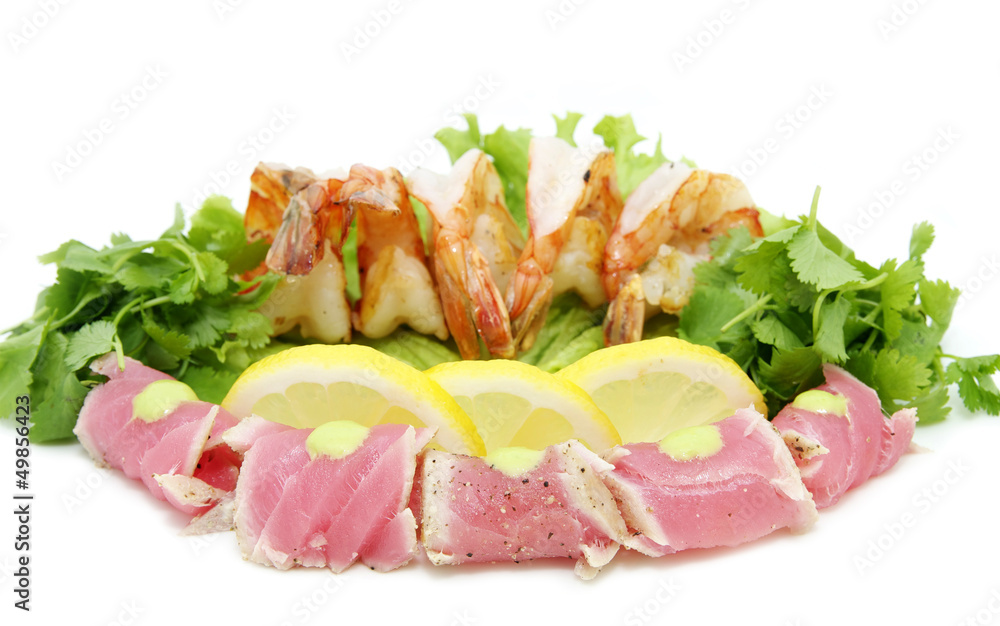 shrimp and tuna with greens and sauce on a white background