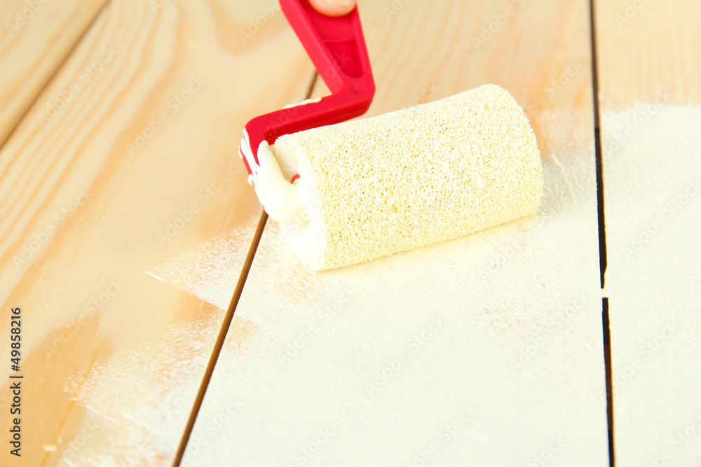 Obraz premium Paint roller brush with white paint, on wooden background