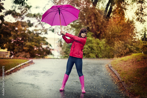 Young woman holding pink umbrella in a park