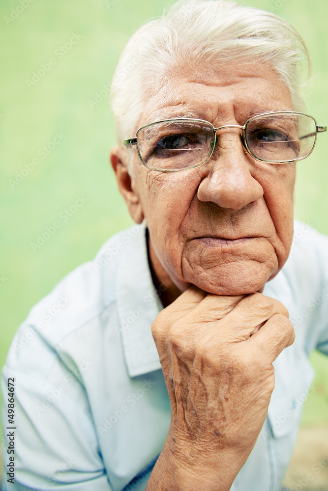 Portrait of serious old man looking at camera with hands on chin Portrait of serious old man looking at camera with hands on chin