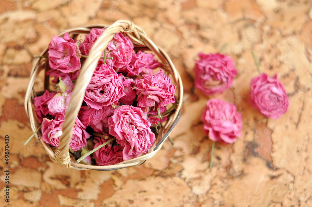 Small pick roses in a handmade straw basket on a wooden table Small pick roses in a handmade straw basket on a wooden table