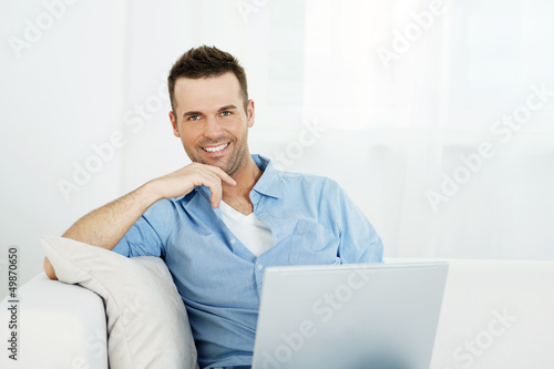 Portrait of handsome man with laptop on sofa