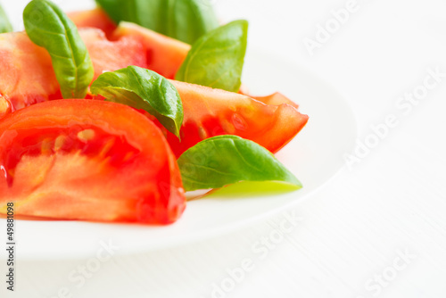 Fresh tomatoes with basil leaves in a plate