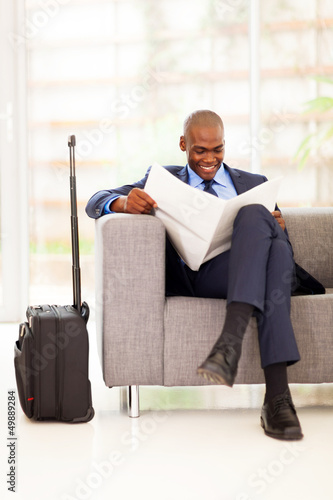 african businessman reading newspaper in airport vip lounge photo