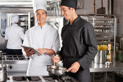 Chef Assisting Colleague In Preparing Food