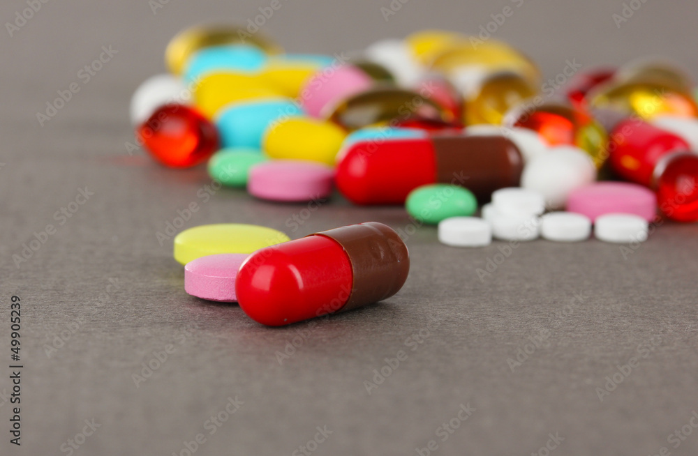 Assortment of pills, tablets and capsules on grey background Assortment of pills, tablets and capsules on grey background