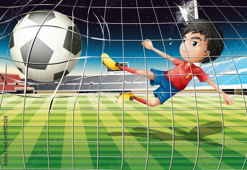 A boy kicking the ball at the soccer field
