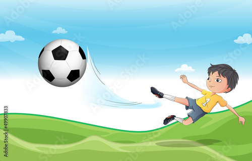 A boy playing football at the hills