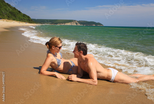 Young caucasian couple sunbathing at the beach