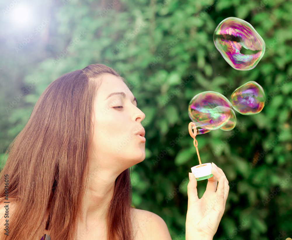 Pretty woman inflating soap-bubbles