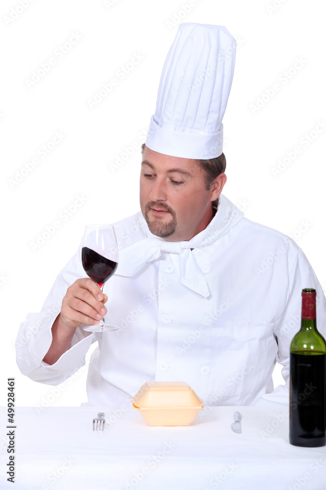 Chef with a glass of red wine and box of junk food Chef with a glass of red wine and box of junk food