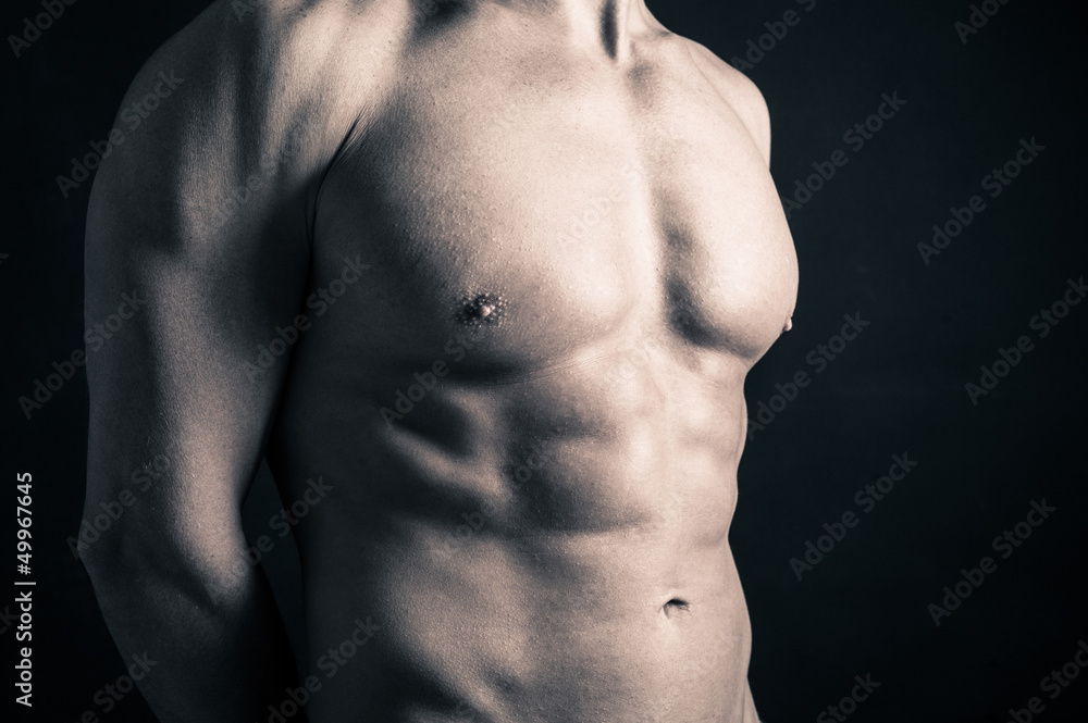 Fototapeta premium Naked man torso against black background.