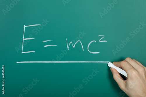 Hand writing relativity formula on blackboard