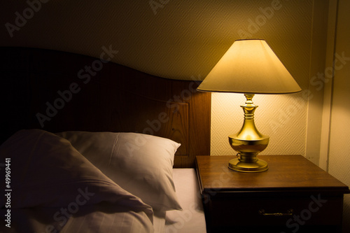 Brass lamp scatter a dim yellowish light over a bed and side table