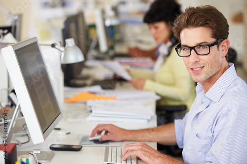 Man Working At Desk In Busy Creative Office