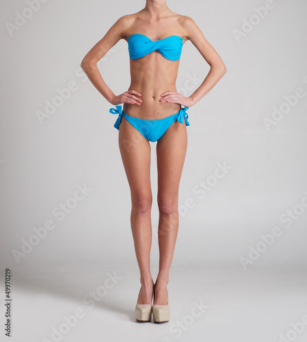 Body of a young and sexy woman posin in a blue swimsuit
