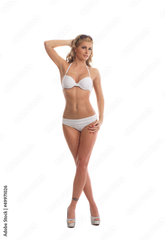 Fototapeta premium A young and fit woman posing in a white swimsuit on white