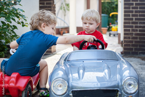 Two little brothers toddlers playing with cars