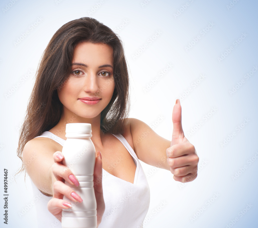 A young and happy brunette holding thumbs up and a bottle