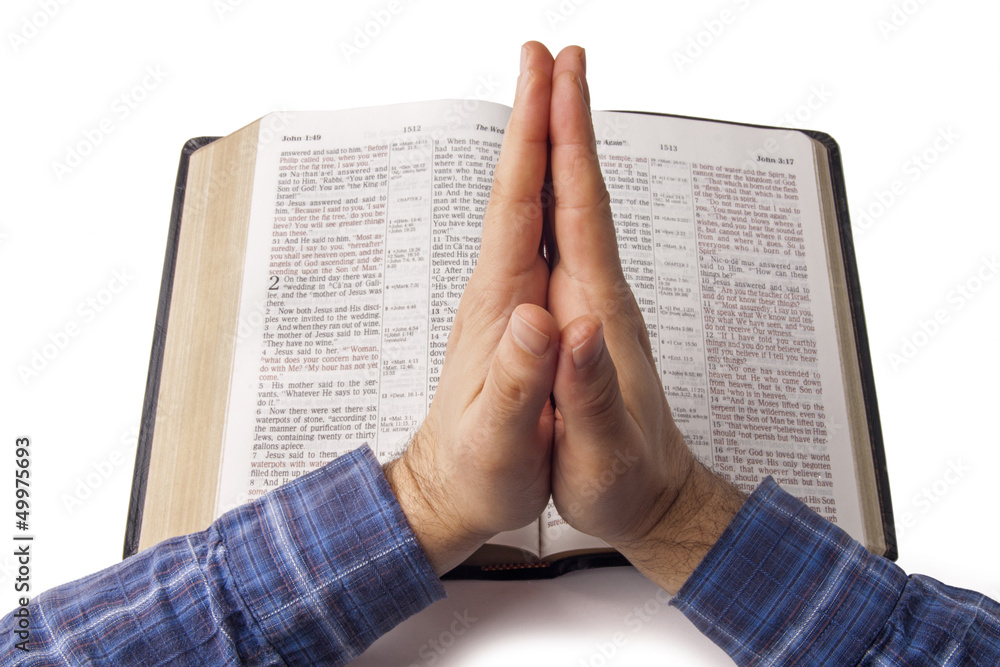 Naklejka premium Praying hands over open bible