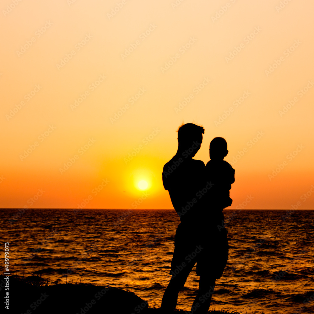 father and son at sunset sea