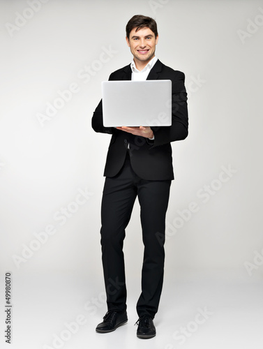 Full portrait of young man with laptop in casuals