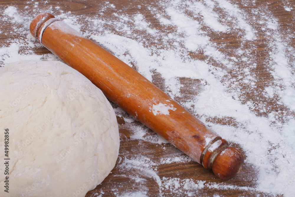 Round the dough and rolling pin on floured table close-up Round the dough and rolling pin on floured table close-up