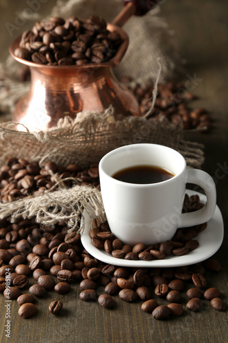 Cup of coffee and pot on wooden background