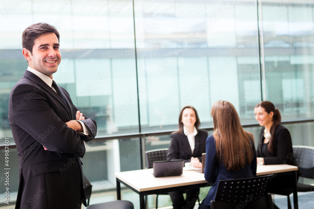 Handsome businessman smiling with his colleagues behind Handsome businessman smiling with his colleagues behind